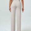 A woman wearing light beige high waisted yoga pants and a cropped top.