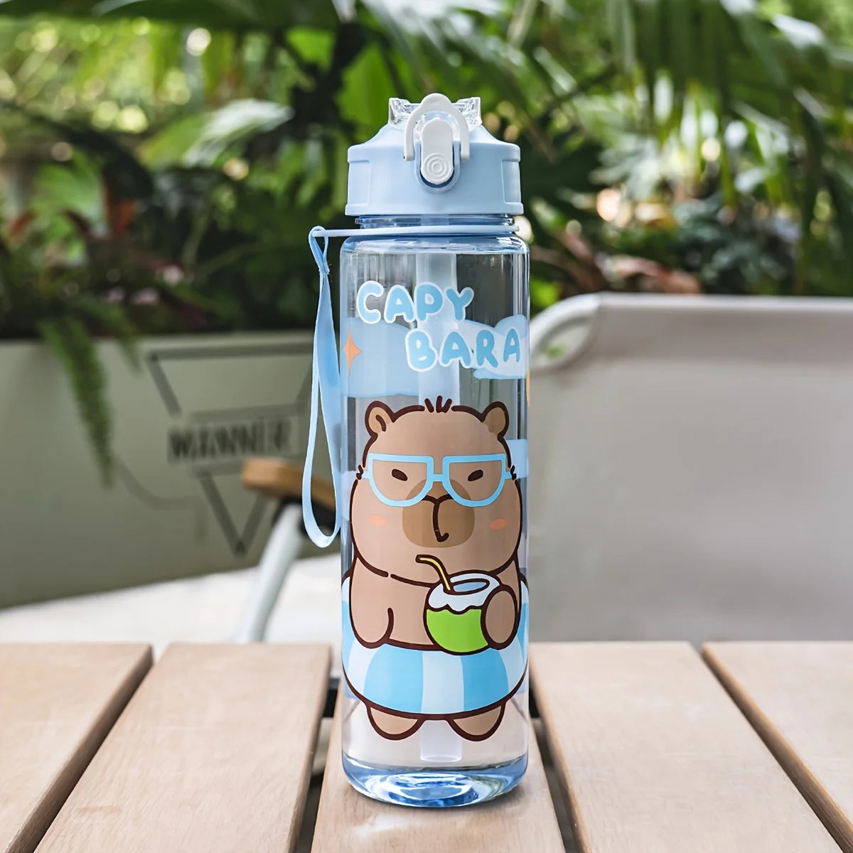 A clear blue cartoon drinking water bottle with a bear face design and a straw, sitting on a wooden surface.