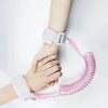 A hand is holding a pink adjustable child safety harness and leash for toddlers.