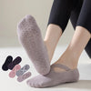 Un par de calcetines de yoga y pilates de color gris claro y ajuste cómodo puestos en un pie.