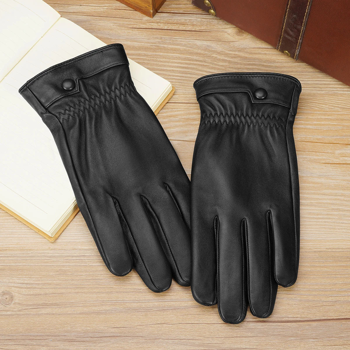 Une paire de gants d'hiver en cuir de brebis noir, pour homme, posés sur une surface en bois clair.