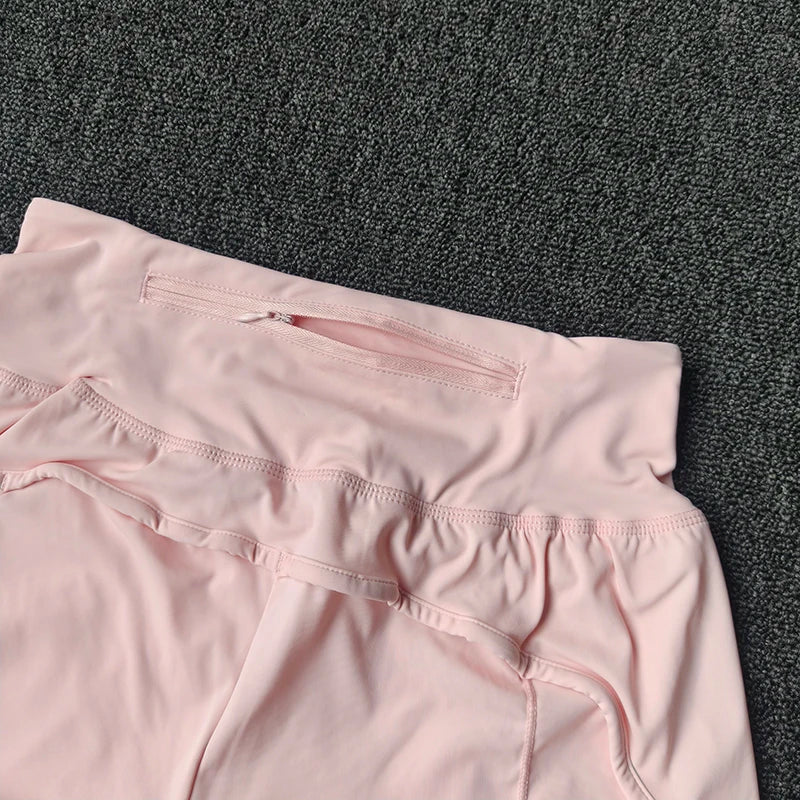 Light pink women's high-waist yoga and fitness shorts laid flat on a dark gray textured surface.