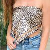 A woman wearing a leopard print satin square scarf top and blue jeans outdoors.