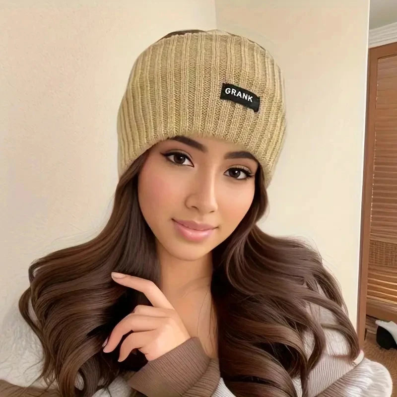 A woman wearing a beige knitted winter headwrap with the word GRANK visible on the front.