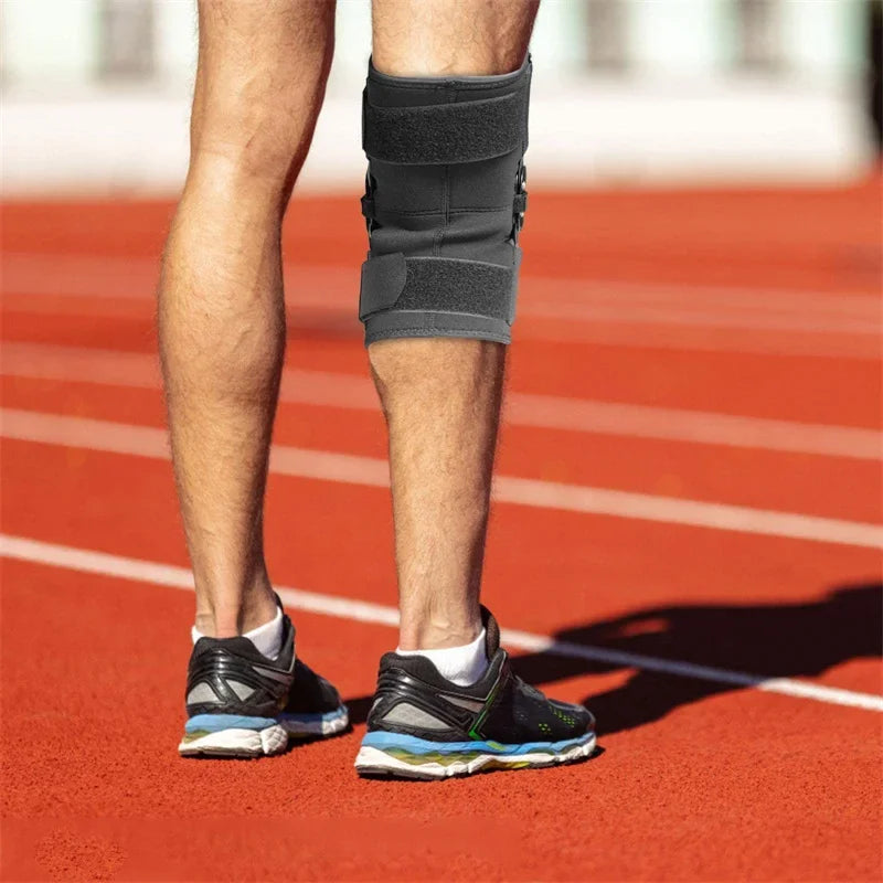 Person mit schwarzem, gelenkartigem Kniebandage mit Stabilisatoren beim Laufen auf einer roten Bahn.