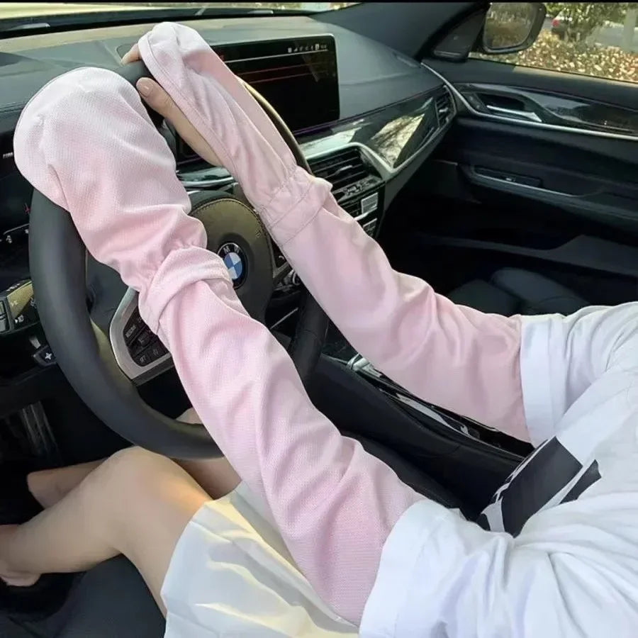 A person wearing pink long-sleeved UV protection arm sleeves is driving a car.