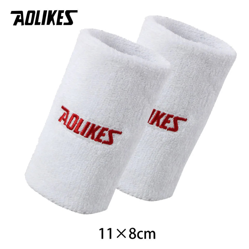 A pair of white towel wristbands with red logo text, measuring 11 by 8 cm.