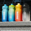 A row of five 550ml Gradient Cycling Water Bottles in various colors lined up on a gray surface.