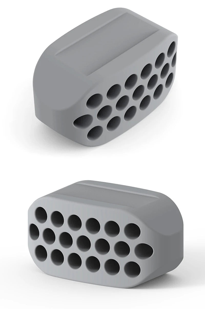 A gray silicone jawline exerciser with multiple circular holes, shown from a top-down angle.