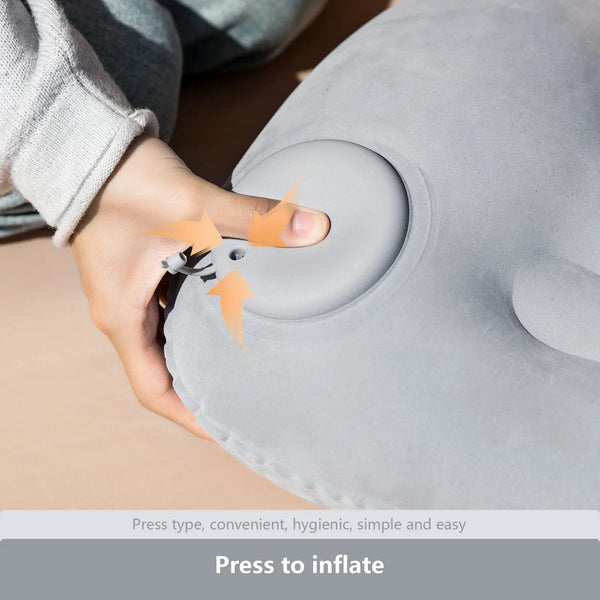 A hand is pressing a button on a gray inflatable pillow designed for neck and lumbar support.
