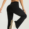 A woman wearing black high-waisted bootcut yoga pants and a black sports top, viewed from the side.