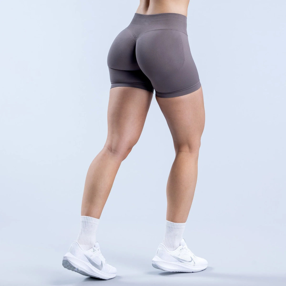 A person wearing seamless high-waisted yoga shorts in a gray color standing and posing.