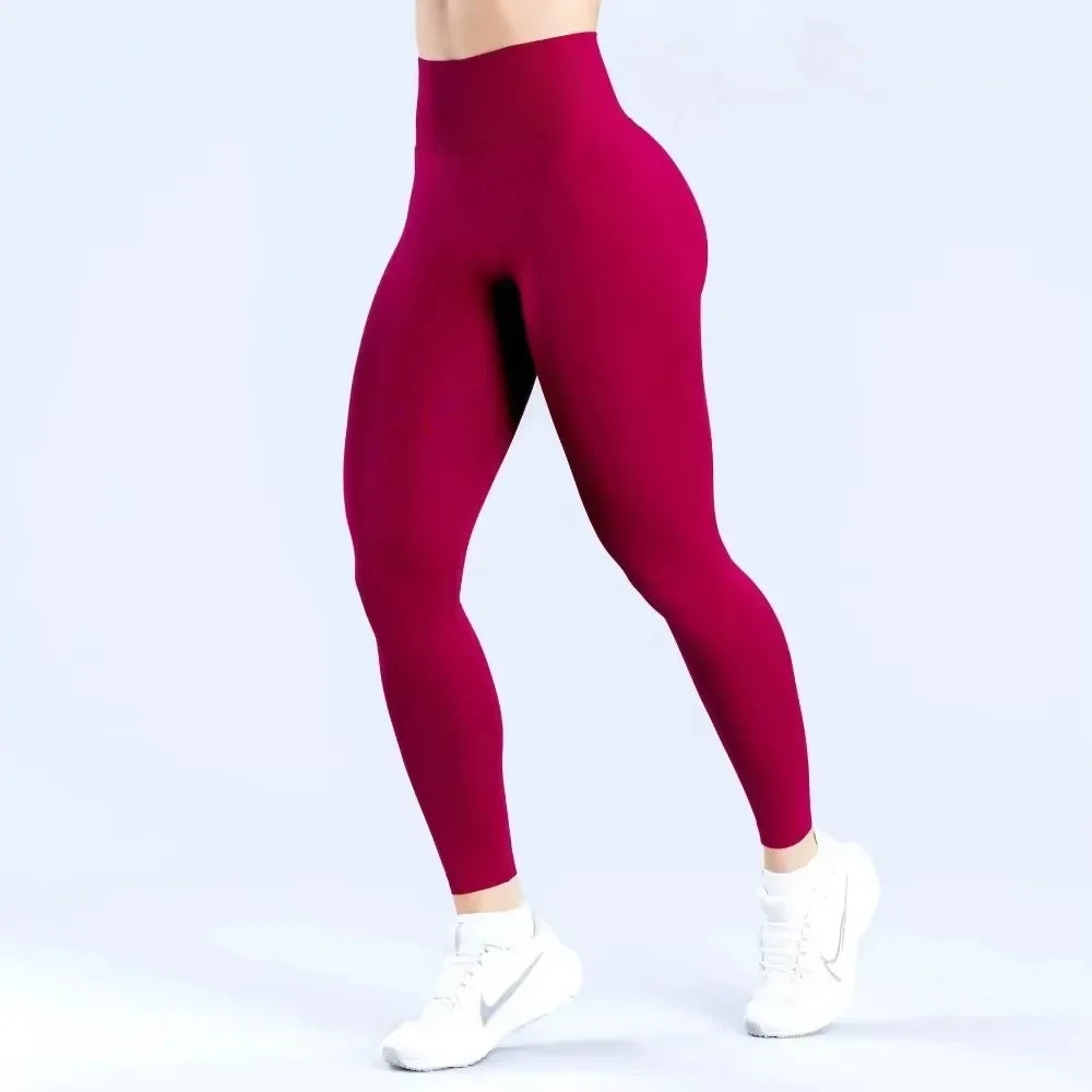 Un modèle portant des leggings de yoga sans couture à taille haute de couleur magenta foncé.