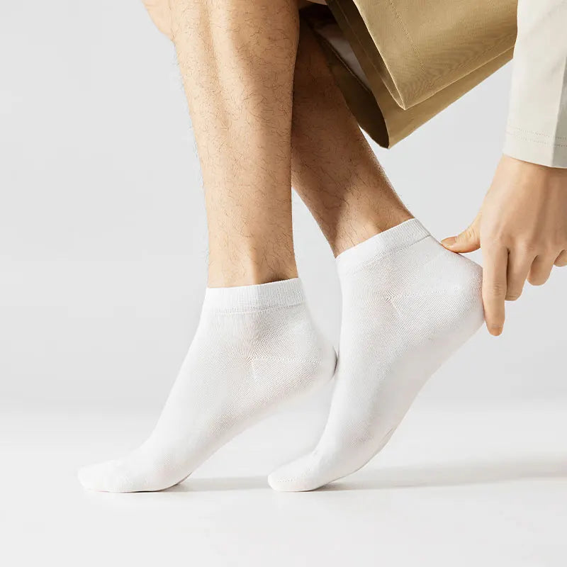 A close-up of a person's legs and feet wearing white men's combed cotton socks.