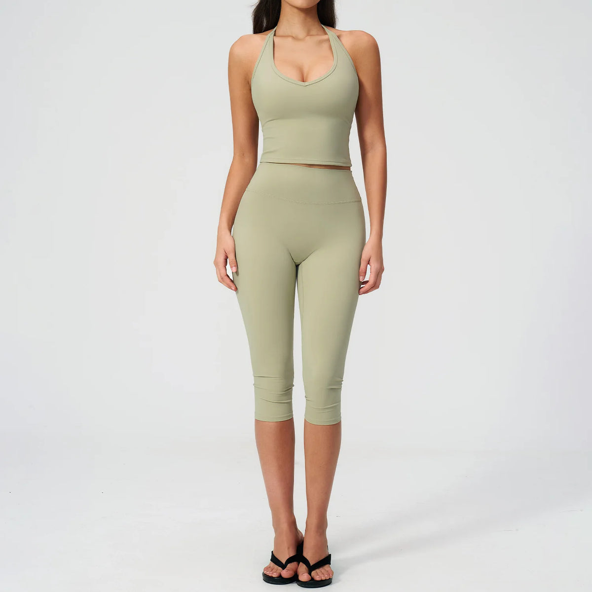 A woman wearing a light olive green women's premium fitness tracksuit top and leggings.