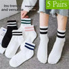 Five pairs of striped socks in black, white, and pink are displayed on a gray surface.