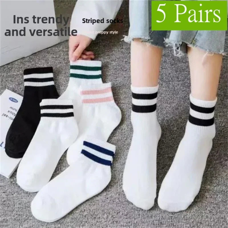 Five pairs of striped socks in black, white, and pink are displayed on a gray surface.