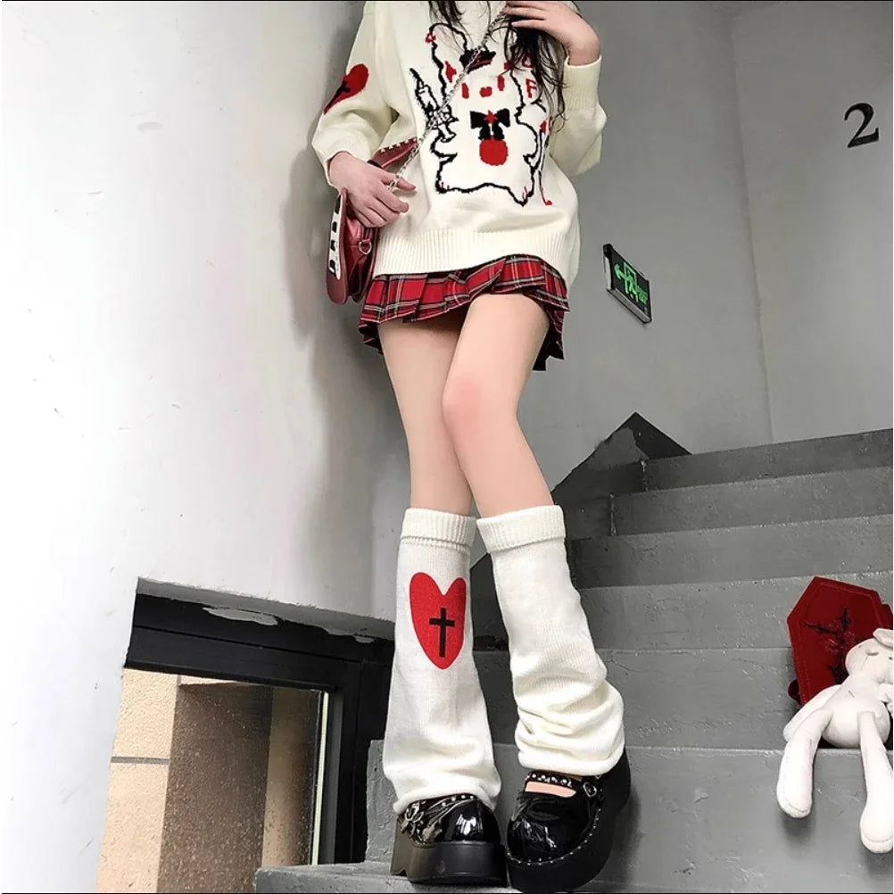 A person wearing white heart-themed leg warmers and black boots, with a white sweater featuring a red heart design.