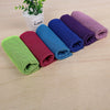 A collection of colorful microfiber cooling towels rolled up on a wooden surface.