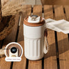 A white thermo mug with a brown lid and an intelligent digital display sits on a wooden surface.