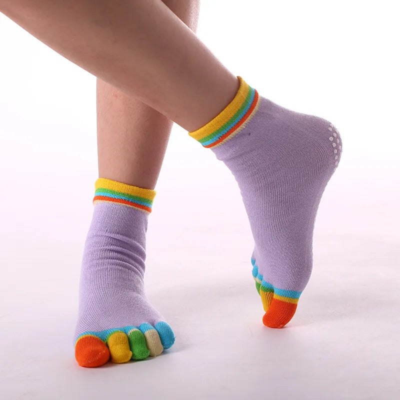 Purple yoga socks with rainbow trim worn on a foot.