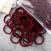 A pile of 50 elastic hair bands in various shades of red and maroon, some packaged in clear plastic.