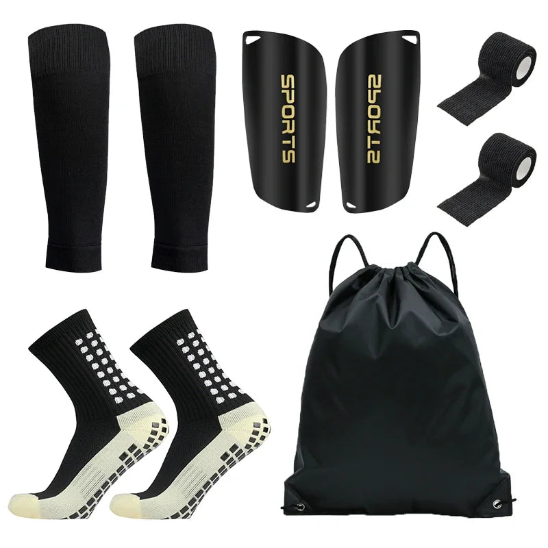 A set of black football training socks and shin guards displayed alongside a black training bag.