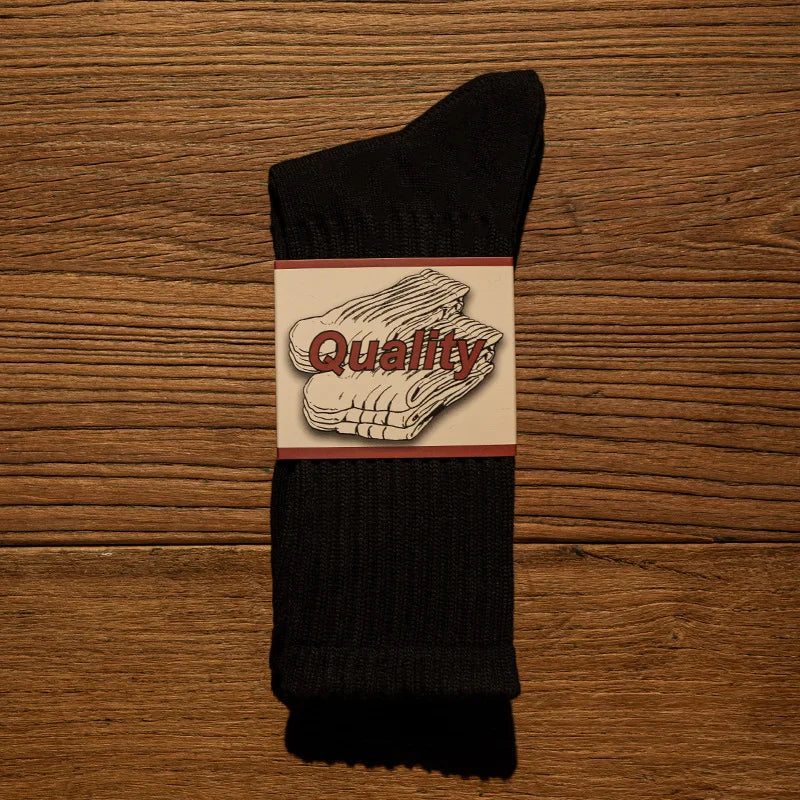 A black tube sock with a rectangular label featuring the word Quality in red text.