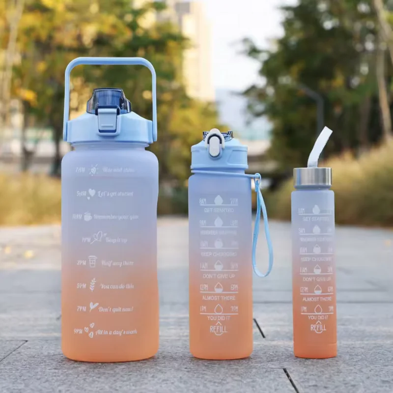 A light blue sports water bottle with a straw and motivational text printed on the body, set against an outdoor background.