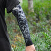 Close-up of a person wearing black long sleeves and an arm covered in black and white skull and tiger tattoo sleeve