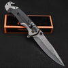 A multi-functional folding survival knife with a silver blade and black handle is displayed on an orange box.