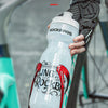Une main tient une bouteille d'eau transparente avec une base en silicone, conçue pour une installation stable sur un cadre.