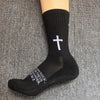 Black athletic socks with a white cross design worn on a foot.