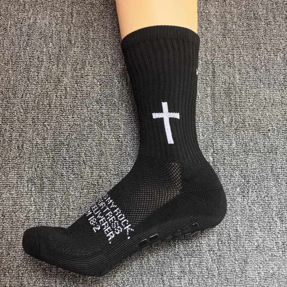 Black athletic socks with a white cross design worn on a foot.