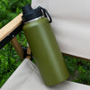 A matte olive green insulated stainless steel vacuum water bottle resting on a light-colored outdoor fabric surface.