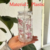 Clear plastic tumbler water bottle with pink bow decorations and a straw being held by a hand.