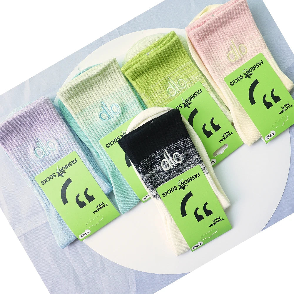 A collection of pastel colored socks in various shades of pink, mint green, and light yellow laid out on a white surface.