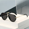 A pair of black retro pilot sunglasses with gold accents resting on a white surface.