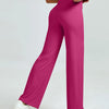 A woman is modeling high waisted magenta yoga pants and white sneakers.