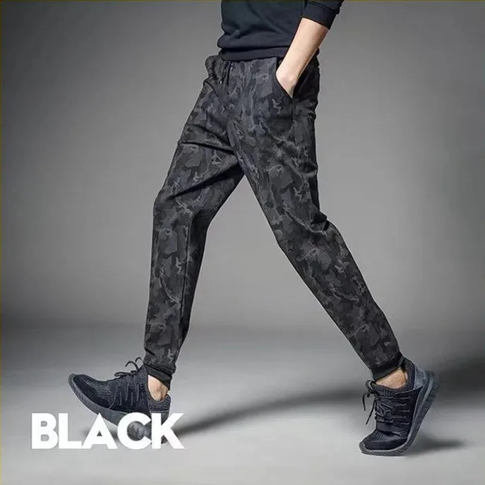 A man wearing black camouflage elastic waist drawstring pants and a dark top, shown from the side.