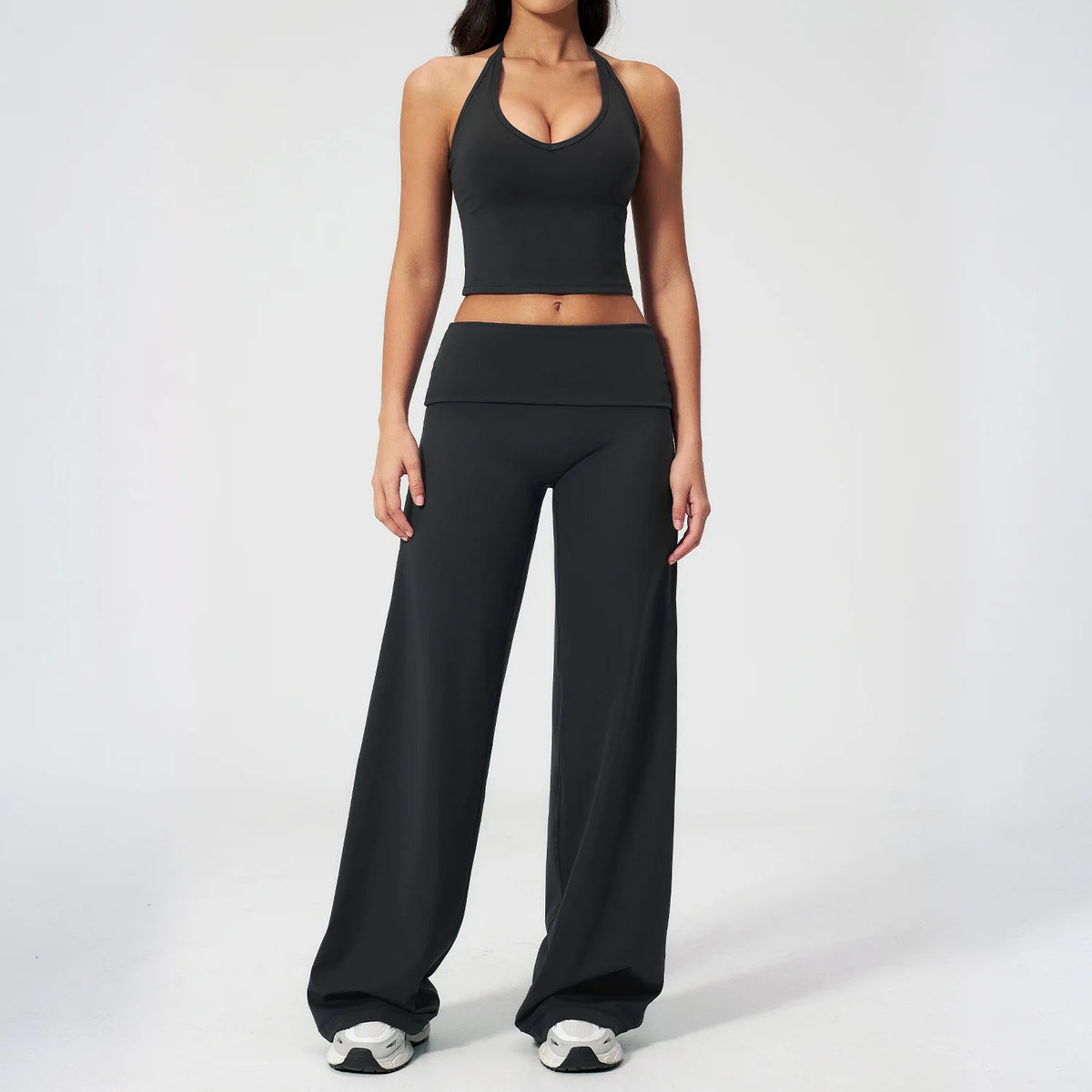 A woman wearing a black women's premium fitness tracksuit top and pants.