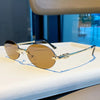 Rimless oval gradient sunglasses with gold-toned metal frame resting on a white surface.