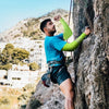 Ein Mann mit leuchtend grünen UV-Schutz-Cooling-Ärmeln klettert eine felsige Klippe im Freien.