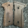 Two wooden custom diamond pattern grips for a firearm resting on a gray textured surface.