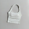 A white seamless yoga and pilates sports bra laid flat on a light gray surface.