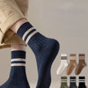 A close-up of navy blue striped socks worn on a foot, with several additional pairs displayed below.
