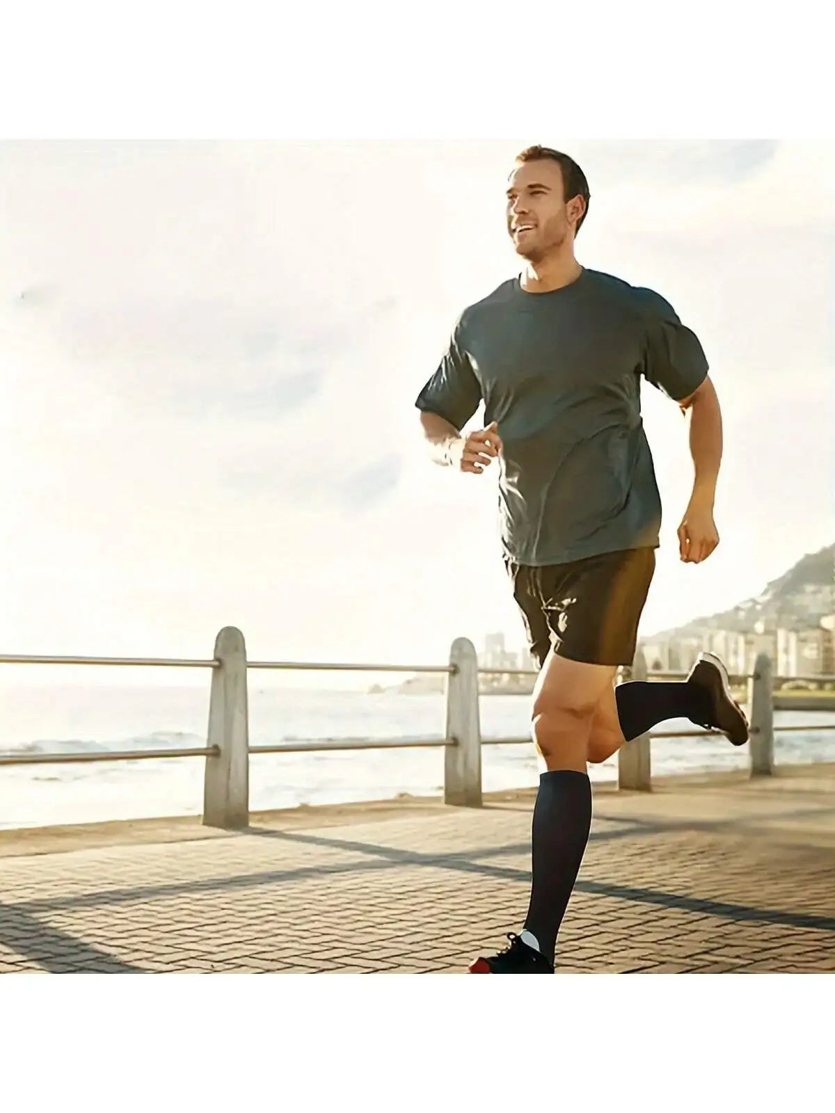 A man running outdoors in a gray t-shirt and shorts near the water.