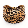 A close-up of a boho leopard print fabric headband rolled into a coil.