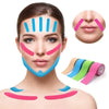 A woman applying colorful kinesiology tape to her face and neck for facial lifting and wrinkle treatment.