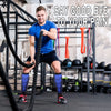 A muscular man exercises with a black cable machine and various fitness equipment, wearing blue compression socks.